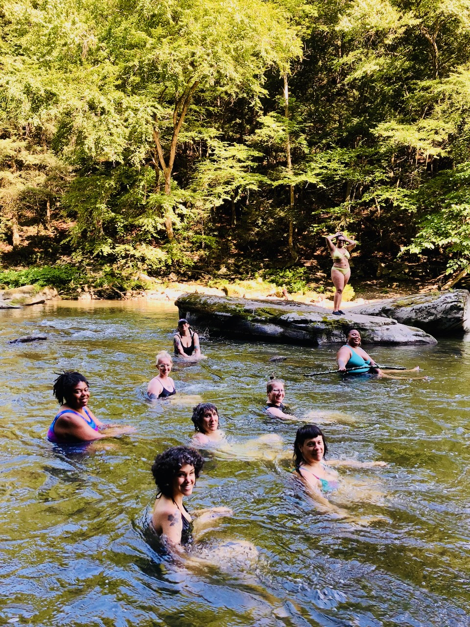 Wild Cherries and Racemes students sitting in a rushing rocky river on the class sleepover weekend.